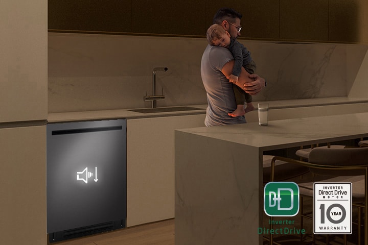 Un homme tenant un enfant endormi tandis qu’un lave-vaisselle silencieux fonctionne en arrière-plan.