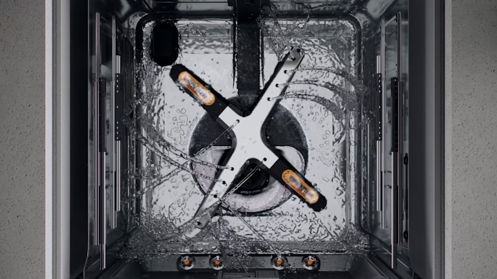 Close-up of a dishwasher spray arm rotating and shooting multiple streams of water upwards.