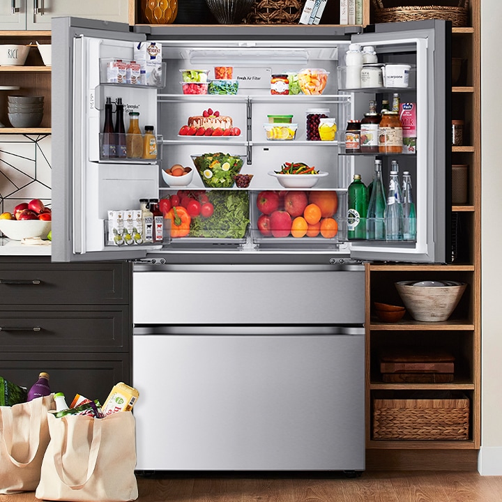 Open stainless steel French door refrigerator filled with fresh food, highlighting the spacious interior and air filter.