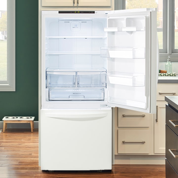White bottom-freezer refrigerator with the top door open, showing glass shelves and clear crisper drawers.