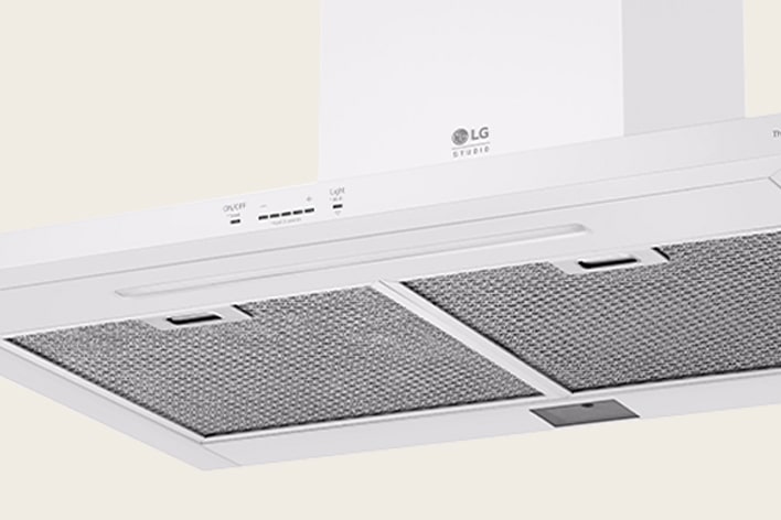 White LG Studio range hood featuring mesh grease filters and a touch control panel for power and lighting.
