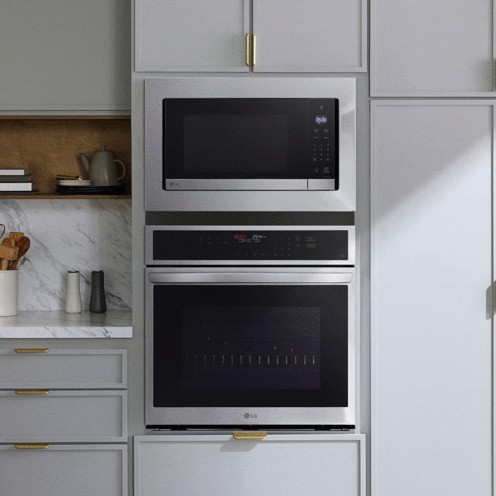 Interior of a stainless steel LG microwave with bright LED lighting illuminating a bowl of pasta on the glass turntable.