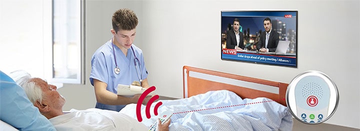 A patient lying in the bed is controlling the TV through a pillow speaker connected to the LN662M.
