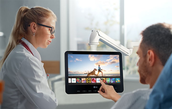 The patient is easily controlling his personal TV using touch, lying in the bed.