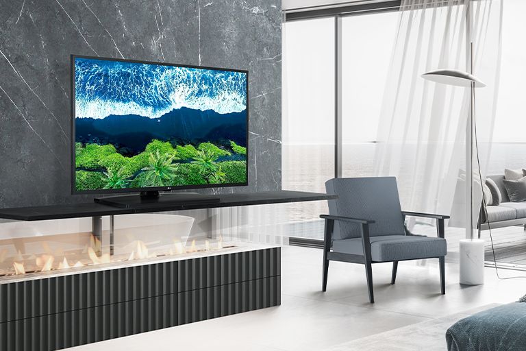 In a simple hotel room overlooking the sea, there is a TV on a wall shelf. The blue sea scenery appears bright and clear on the TV screen.