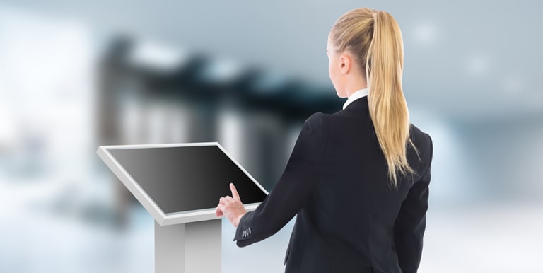 A woman is touching a lower installed TNF3K. The TNF3K is installed tilted toward the woman so she can see the display content well.