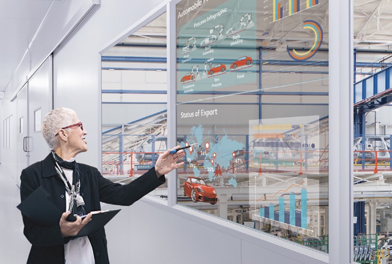A woman understands her work by looking at the transparent display installed in the office's windows.