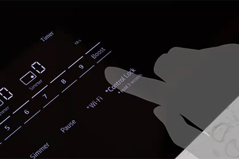 Hand activating the control lock on an LG induction cooktop, which prevents accidental use and provides added safety for households with children.