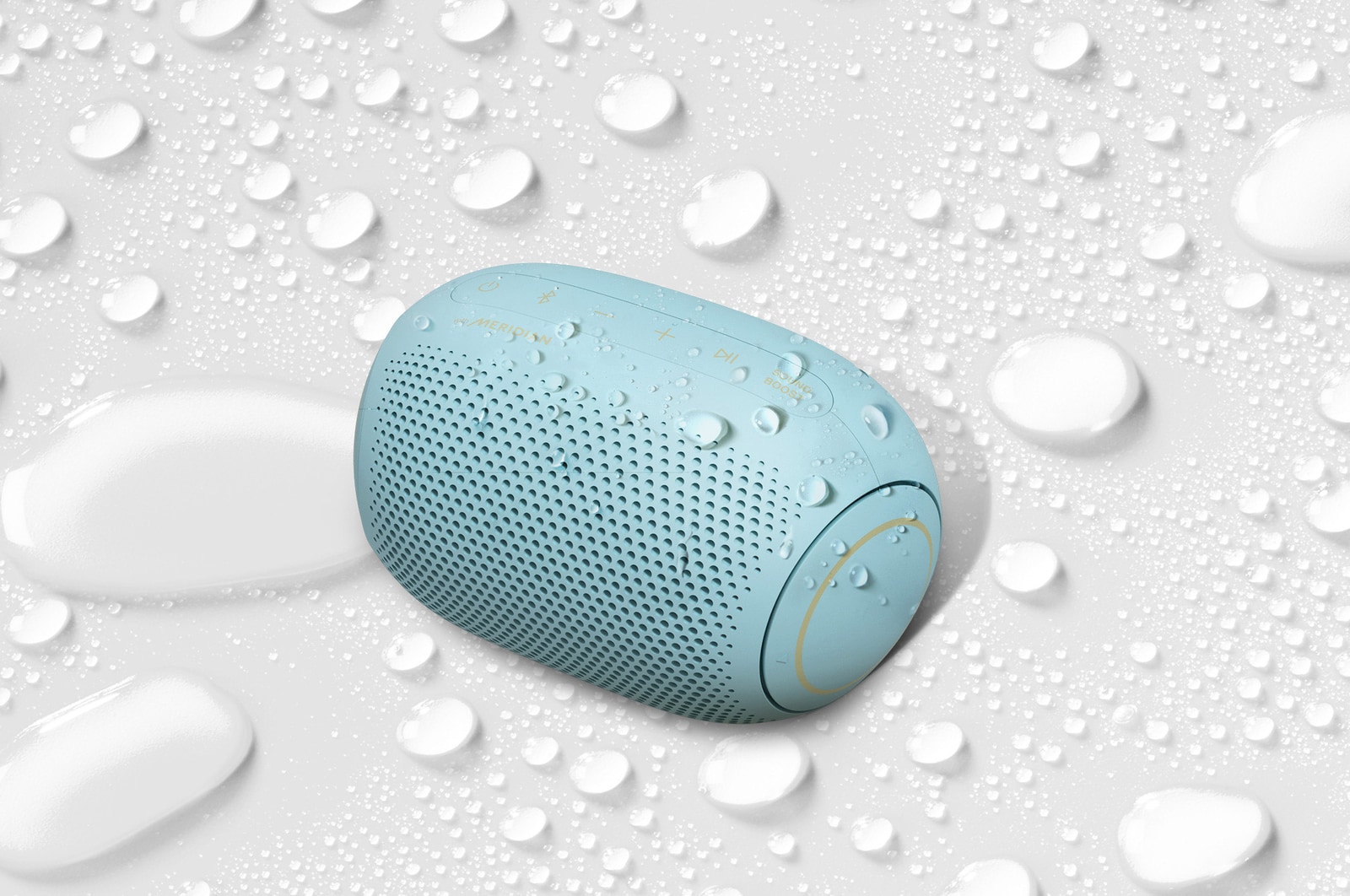 A top view of an LG XBOOM Go on a white surface with water droplets