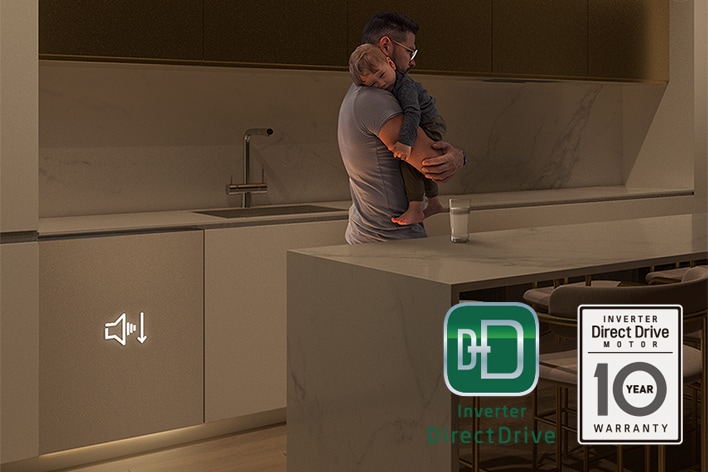 Man holding a sleeping child while a quiet dishwasher runs in the background