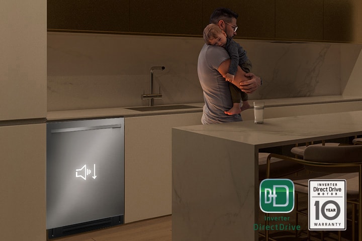 Man holding a sleeping child while a quiet dishwasher runs in the background