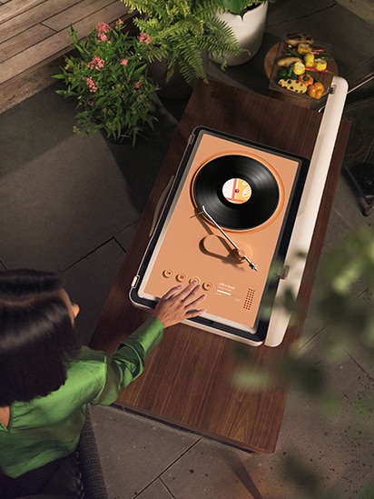 StanbyME Go is placed on the wooden table, and the screen shows coral turntable music skin.