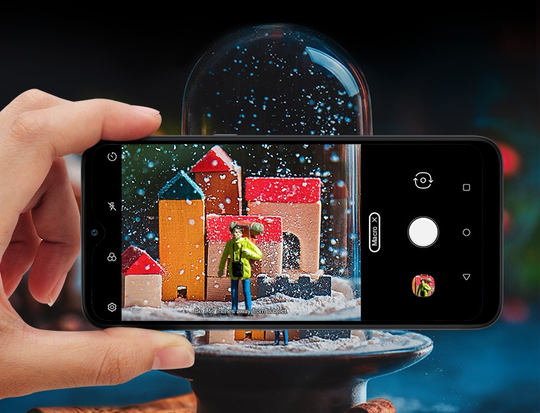 Closeup of someone holding a smartphone taking a picture of a snowball