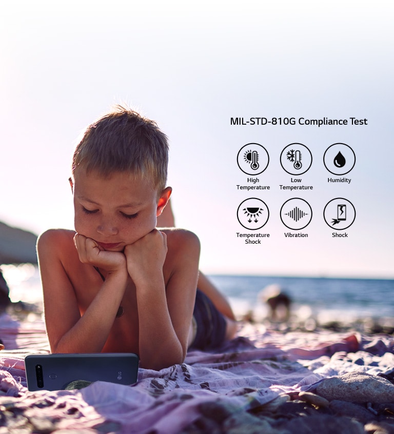 Child lying on the beach and watching a movie on his smartphone