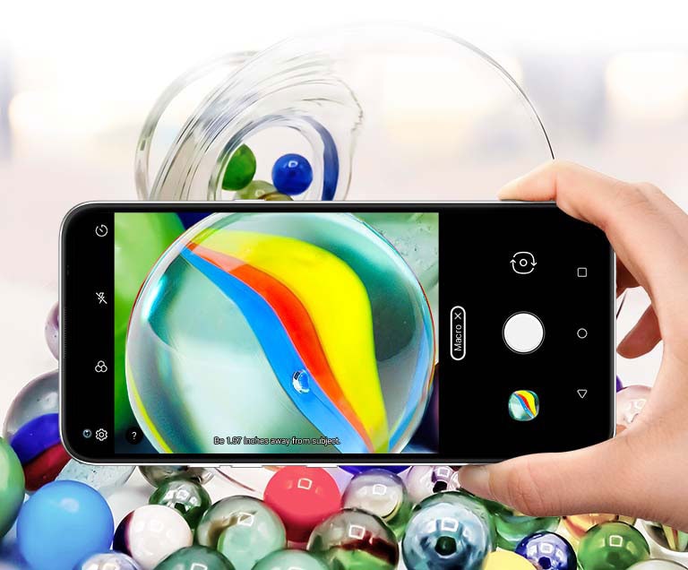 Closeup of someone holding a smartphone taking a picture of some marbles
