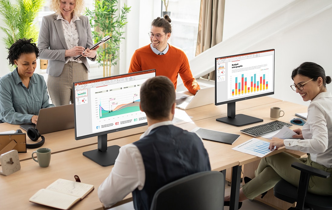 Employees sitting at office desks and having a conversation.