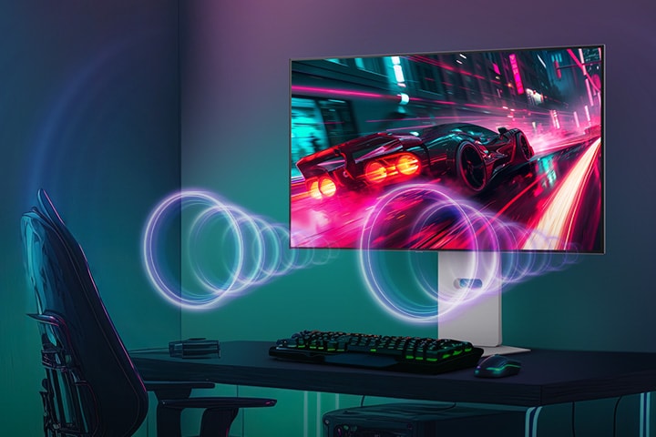 The monitor screen shows a racing game, while sound is coming from the speakers at the bottom of the monitor.