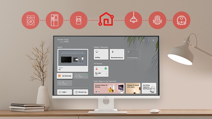 On the table's monitor screen, the Home dashboard is displayed, and at the top of the image, there are icons of household appliances such as washing machines, refrigerators, vacuum cleaners, etc., which can be controlled via the LG ThinQ app.