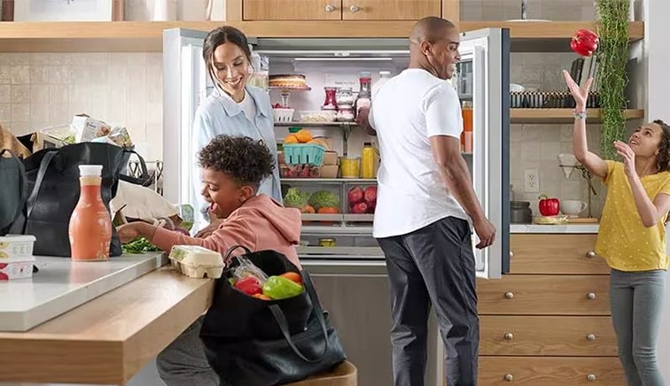 The family is taking out food in front of the refrigerator