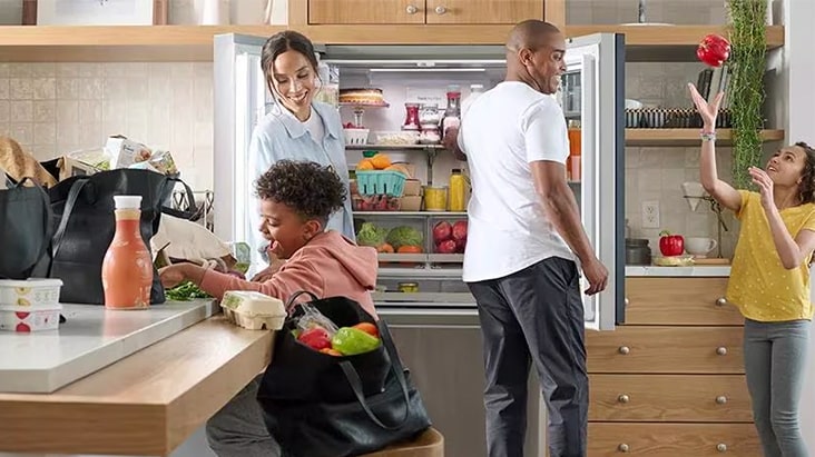The family is taking out food in front of the refrigerator	