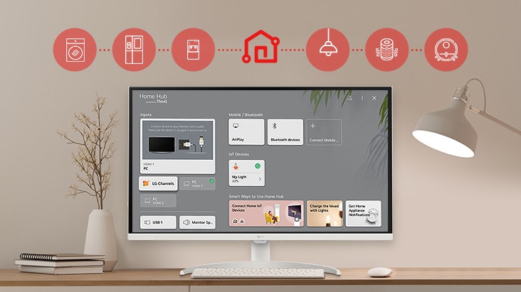 On the table's monitor screen, the Home dashboard is displayed, and at the top of the image, there are icons of household appliances such as washing machines, refrigerators, vacuum cleaners, etc., which can be controlled via the LG ThinQ app.
