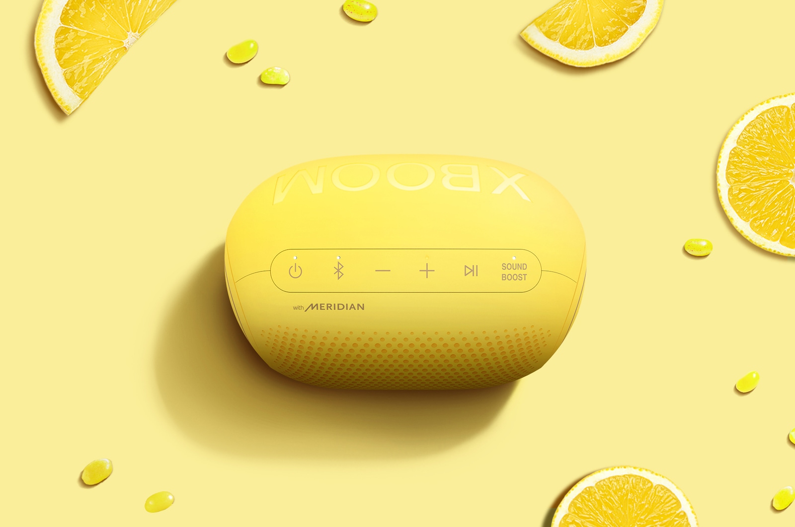 Lemons, jellybeans, and an LG XBOOM Go PL2S are placed on a yellow background.