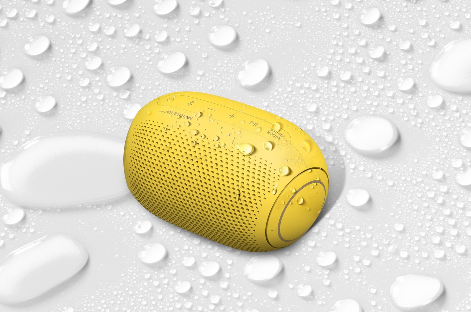 A top view of an LG XBOOM Go on a white surface with water droplets