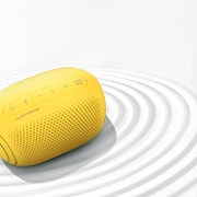 A top view of an LG XBOOM Go on a white surface with a ripple effect