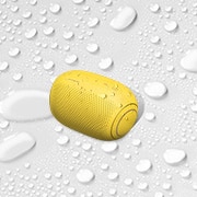 A top view of an LG XBOOM Go on a white surface with water droplets
