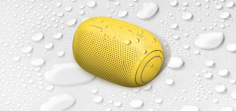 A top view of an LG XBOOM Go PL2B on a white surface with water droplets