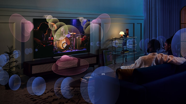 A woman sits on a couch watching a concert with bubbles depicting surround sound around her