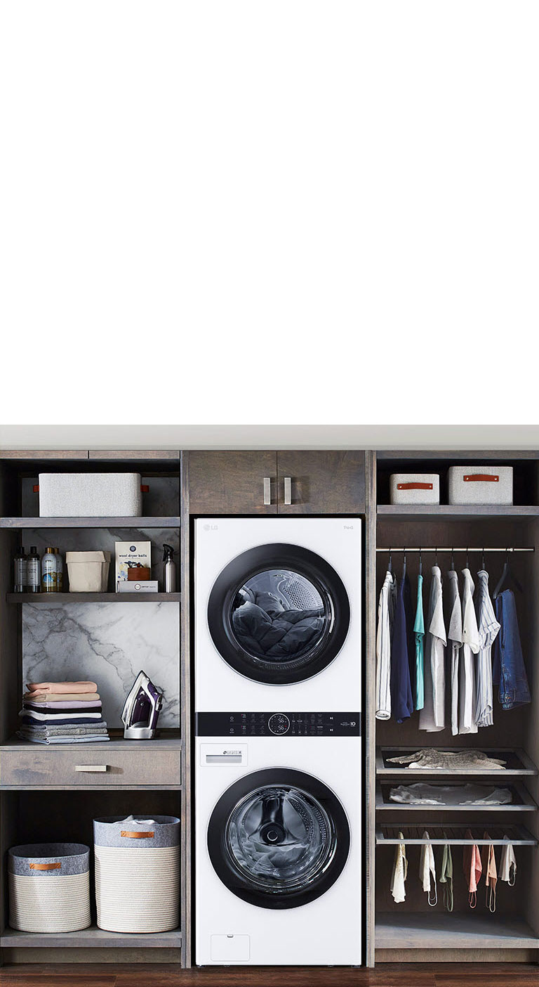 Modern laundry room with stacked LG washer and dryer beside organized shelves and hanging clothes.