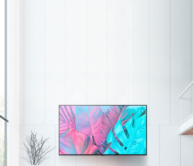 A large flatscreen TV mounted against a white wall. The screen shows large leaves in bright colours.