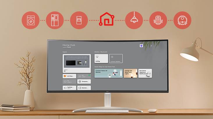 On the table's monitor screen, the Home dashboard is displayed, and at the top of the image, there are icons of household appliances such as washing machines, refrigerators, vacuum cleaners, etc., which can be controlled via the LG ThinQ app.	