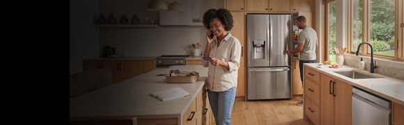 People in a modern kitchen shopping online with an LG refrigerator and dishwasher in the background.