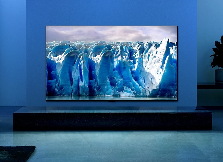 The video shows a close-up of iceberg image and there is a visual effect of blue circuit running on iceberg image. Scene changes to show a TV hanging on living room with blue lighting and background. There is a vast iceberg on TV screen.