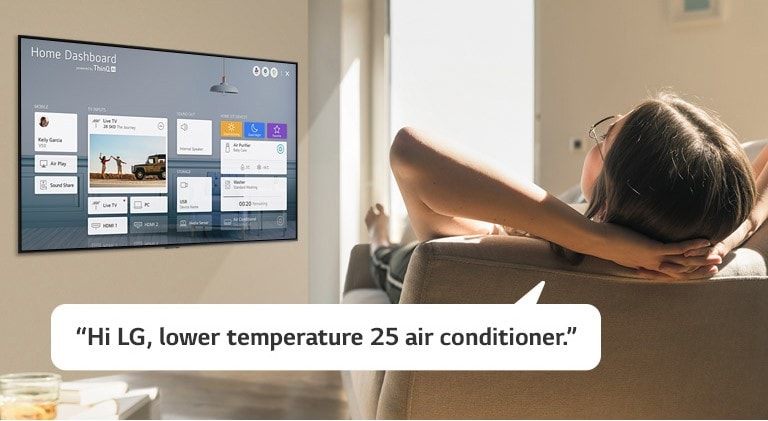 Woman lying on a sofa telling TV to lower the temperature with Home Dashboard on the TV screen