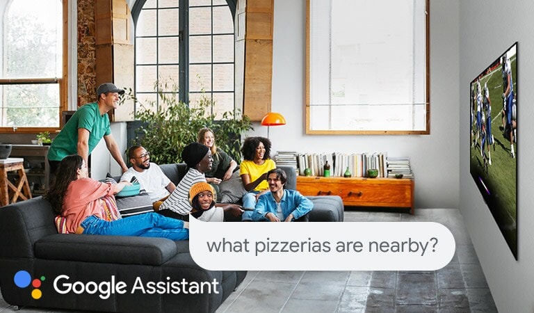 Woman watching football on TV with friends and asking the Google Assistant what pizzerias are nearby