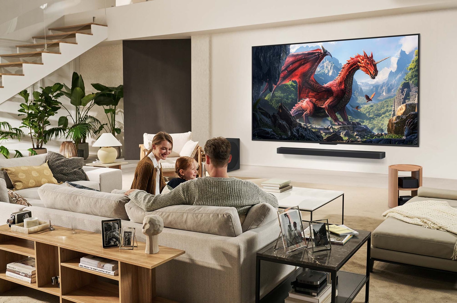 Une famille est assise sur un canapé face à un LG QNED TV monté sur un mur au-dessus d’une LG Soundbar. La boîte Zero Connect se trouve à l’intérieur d’une table basse.