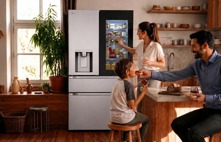 Une famille dans une cuisine moderne et chaleureuse, une femme cherche des produits dans un réfrigérateur LG noir tandis qu'un homme nourrit un jeune enfant à l'îlot de cuisine.
