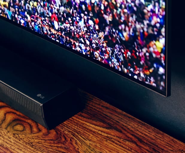 Un téléviseur fixé au mur sur un meuble en bois affichant une scène vivante de stade de football