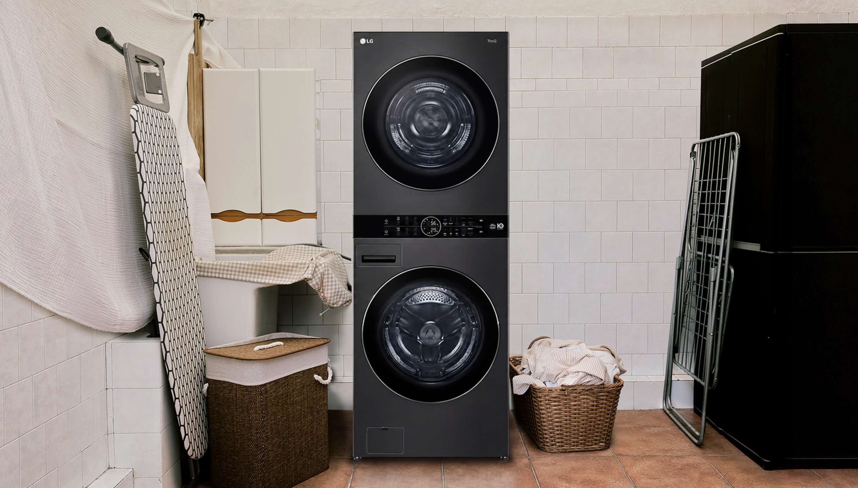 LG WashTowerᴹᴰ dans une buanderie carrelée, à côté d'un panier à linge rempli de serviettes.