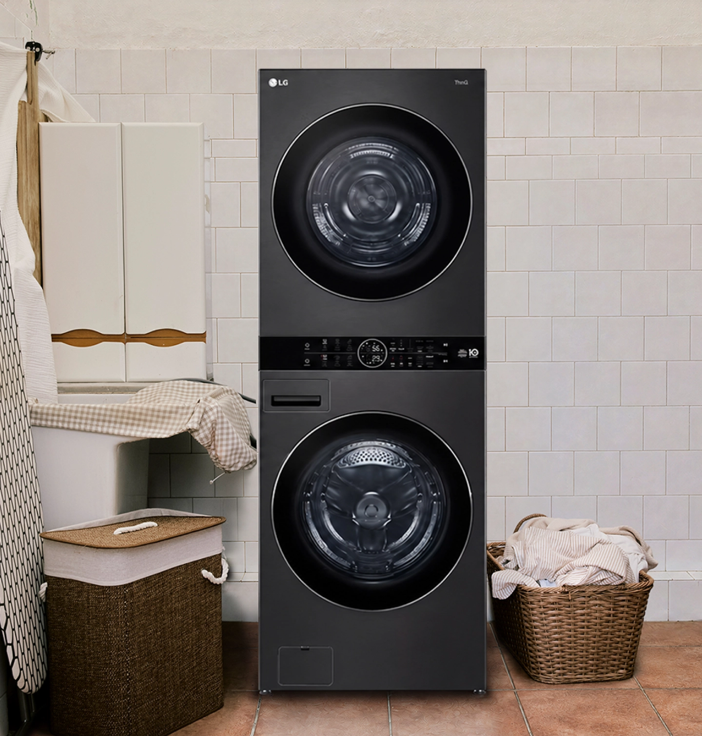 Gros plan d’une LG WashTowerᴹᴰ dans une buanderie carrelée, à côté d’un panier à linge en osier.