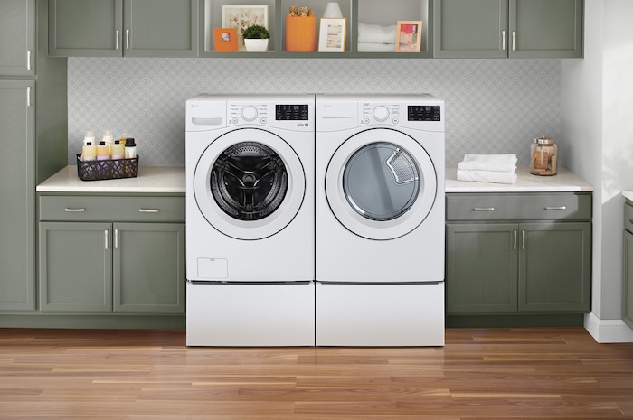 L'ensemble lave-linge et sèche-linge frontal LG (WM3470CW) Blanc, présentant son esthétique classique et son intégration harmonieuse sur socles dans une buanderie moderne.