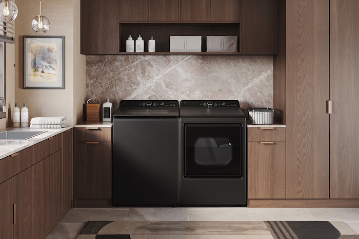 L'ensemble lave-linge et sèche-linge à chargement par le haut LG (WT8400CB) en Noir Acier, illustrant son design haut de gamme intégré harmonieusement dans une buanderie luxueuse avec marbre.