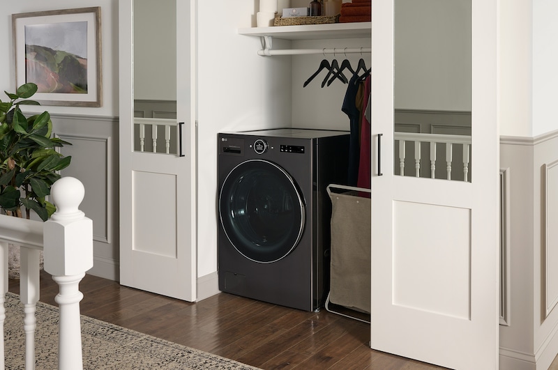 Le lave-linge séchant frontal LG WM6998HBA en Noir Acier, illustrant son design tout-en-un peu encombrant et son installation discrète dans un placard.