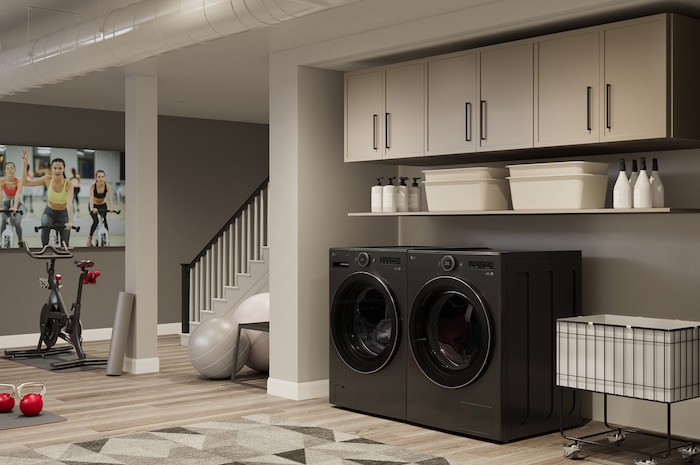 L'ensemble lave-linge et sèche-linge frontal LG (DLHC6702B) en Noir Acier, mettant en valeur son design premium et son intégration harmonieuse dans un espace utilitaire moderne faisant office de salle de sport.