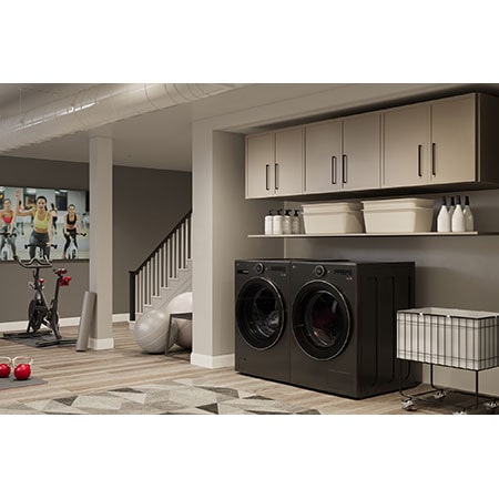 L'ensemble lave-linge et sèche-linge frontal LG (DLHC6702B) en Noir Acier, mettant en valeur son design premium et son intégration harmonieuse dans un espace utilitaire moderne faisant office de salle de sport.