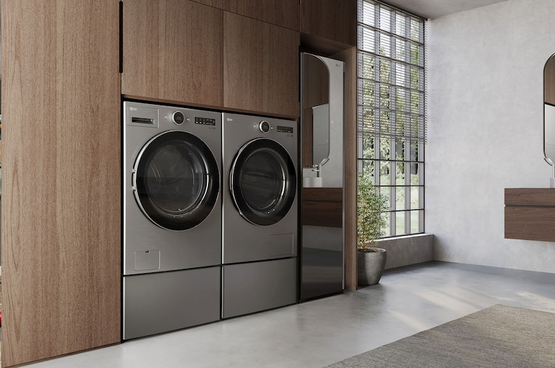 L'ensemble lave-linge et sèche-linge frontal LG (DLHC5502V) en Acier Graphite, mettant en valeur son design premium et son intégration parfaite et affleurante dans des armoires en bois modernes.