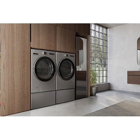 L'ensemble lave-linge et sèche-linge frontal LG (DLHC5502V) en Acier Graphite, mettant en valeur son design premium et son intégration parfaite et affleurante dans des armoires en bois modernes.